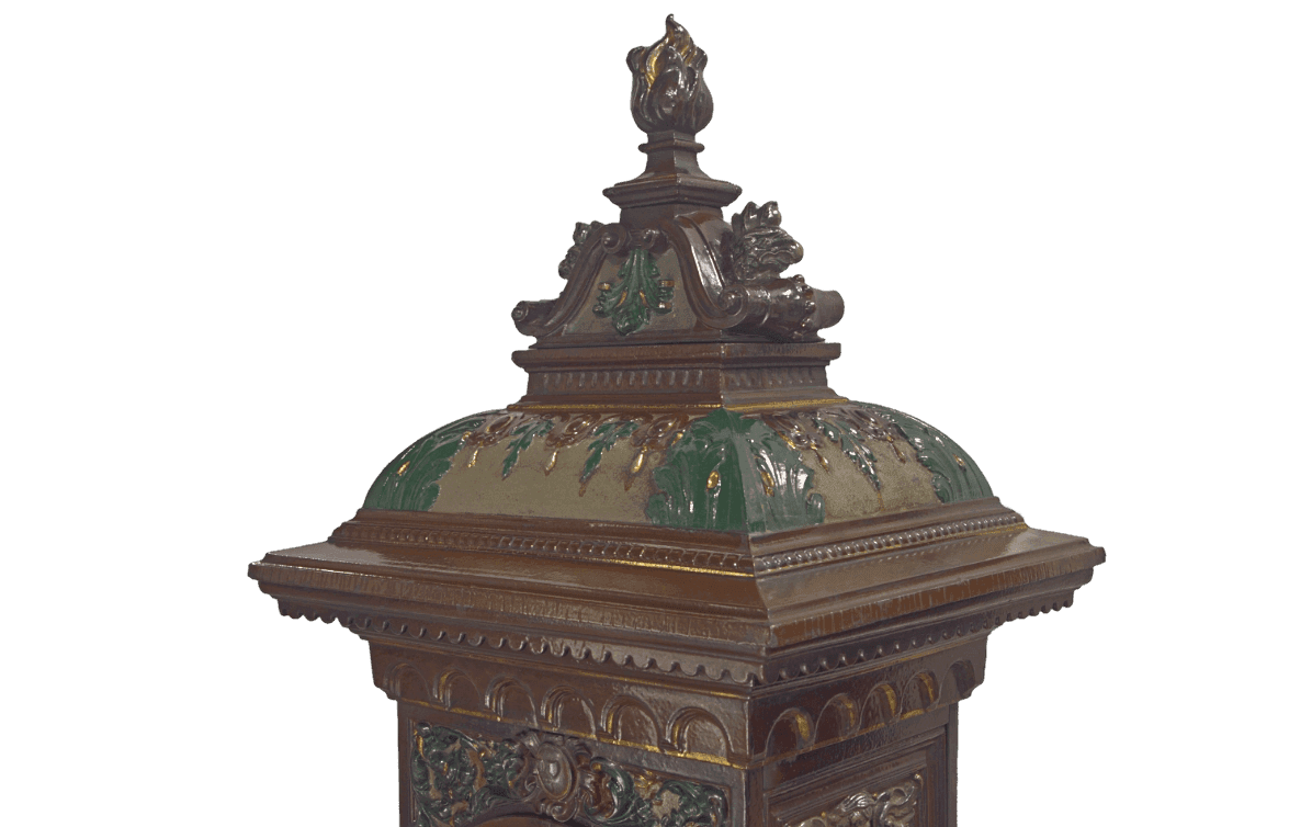 Majestätische, mehrfarbig glasierte Krone eines gusseisernen, antiken Ofens.